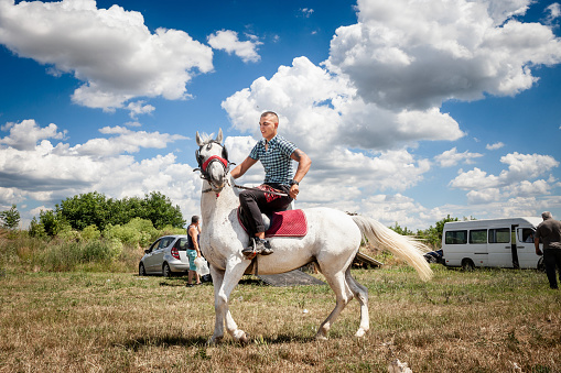 Picture of a young man riding horse in the Rumska Straparijada market, while drinking beer.