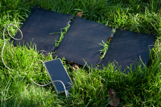 istock Portable solar battery and mobile phone on green grass. Charging electronic gadgets on a hike, during outdoor recreation. Ecological energy concept. 1465337361