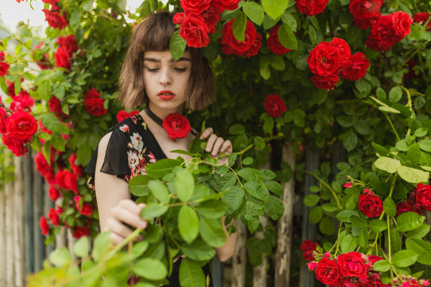 Fabulous asian girl with red lips in dress on awesome summer background. Rose garden