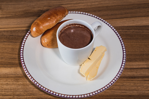 Traditional colombian breakfast, hot chocolate with cheese and bread. On a wooden table. Copyspace