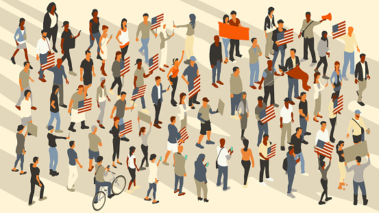 A crowd of around 70 protesters march while they hold picket signs with images of the United States flag. One woman holds her fist in the air, another holds up a megaphone, and a man waves a flag. Contemporary people wear casual clothing. Vector people are shown in a 16x9 artboard.