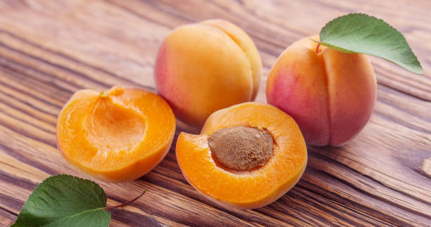 istock fresh ripe apricots with leaves on a wooden table 1465339774