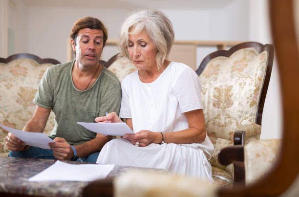 istock Aged woman and man sign documents sitting in room interior 1465341932