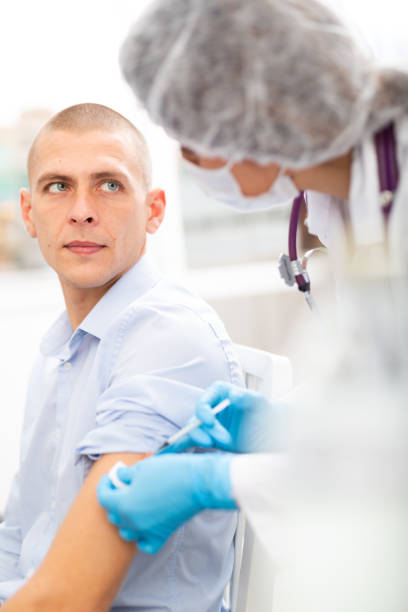 istock Professional nurse giving vaccine injection to man 1465343448