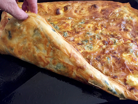 Female hand showing Turkish pastry food borek in a tray