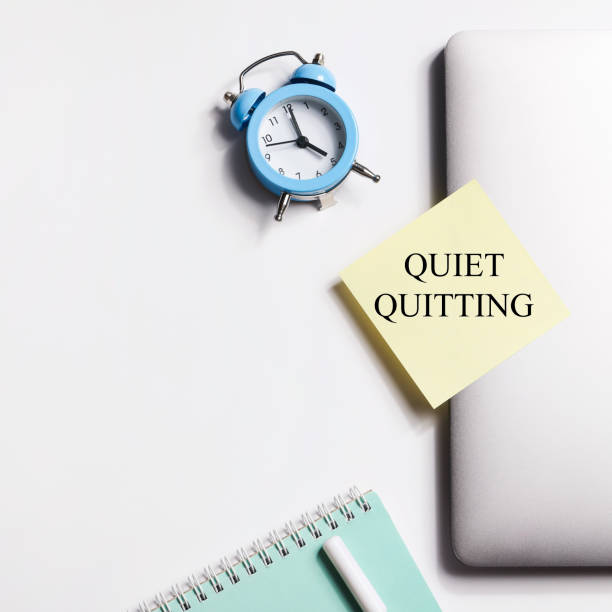 istock quote 'Quiet quitting' on yellow sticker on computer with clock and notebook. work life balance concept. post covid life philosophy. square 1465344873