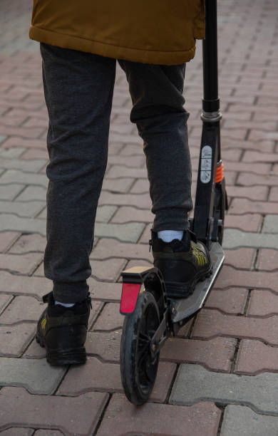 istock Teenager rides a scooter on a brick road 1465345697