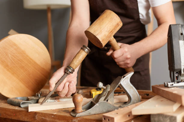 istock Closeup portrait of unknown faceless man master wearing brown apron using mallet and chisel for making wooden furniture, craftsman working in his joinery workshop. 1465346787