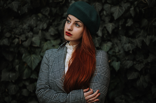 Photoshooting in nature. Girl with red curly hair. Well dresses and with little make-up.  Beautiful young woman enjoying photoshoot with winter idyllic moment.