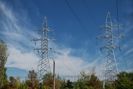Tower with high-voltage energy transmission wires against the blue sky. High-voltage tower. Electrical wires and fuses. Energy business. Energy industry. Import and export of energy. Blue sky.
