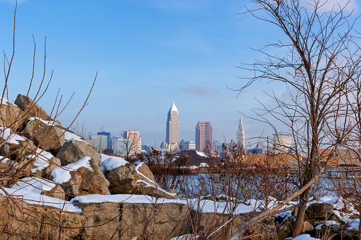 Views of Clevelands skyline beyound boulders and shrubs along the wintery shoreline of Lake Erie at Edgewater Park in Cleveland, Ohio.