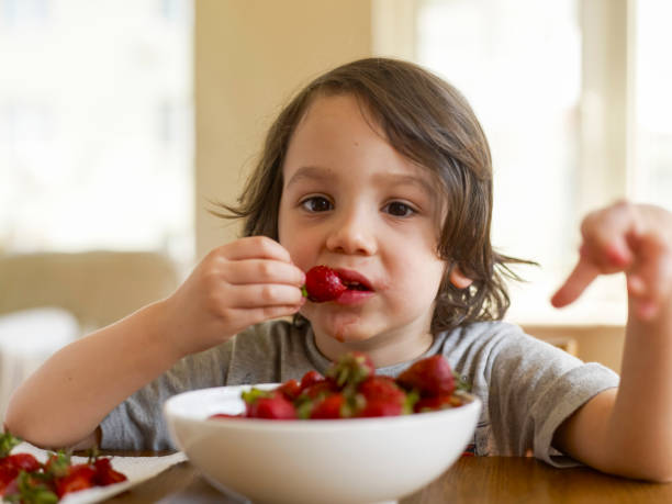 istock Cute kid eating strawberries 1465350719