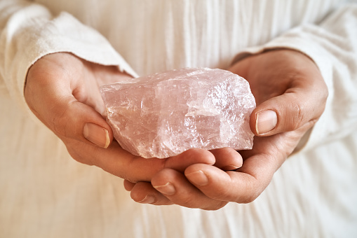 Hands holding a rose quartz stone