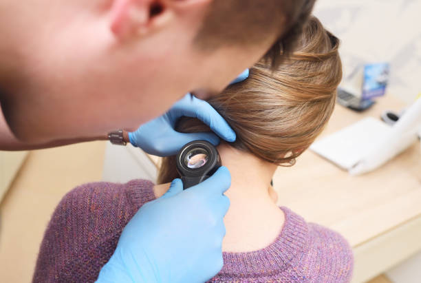 dermatologist examines a mole on the patient's neck using a special device - a dermatoscope. Prevention of skin cancer - melanoma. stock photo