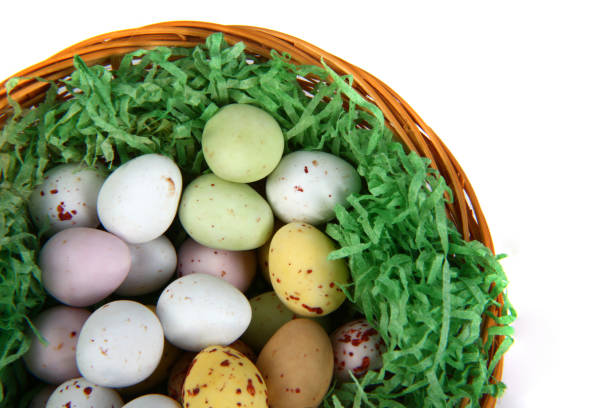Easter image with basket of decorative eggs wrapped in color patterned paper and empty white note on pastel pink background. Easter greeting card. Mock up. Copy space. Horizontal orientation.