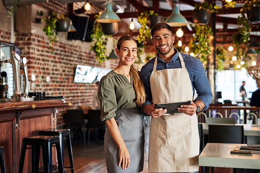 Restaurant, portrait and small business owner or team happy and smiling in coffee shop or cafe. Entrepreneur, waiter and collaboration with startup by people in partnership with tablet for sales data