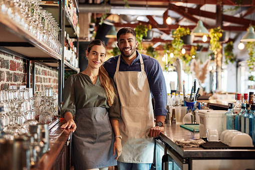 Small business, pub owner and portrait of couple, smile at cafe counter and hospitality startup investment. Success, confidence and man with woman in service industry, management and bespoke wine bar