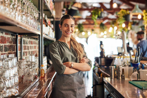 Small business, bartender and portrait of owner, woman with smile at pub counter, hospitality startup investment in alcohol sales. Success, confidence and service industry manager at bespoke wine bar stock photo
