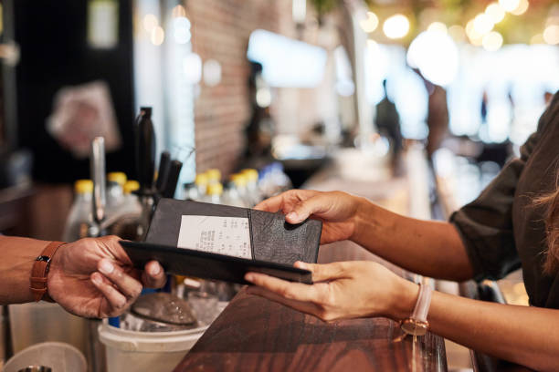 Hands with bill, food service and people in restaurant, customer with receipt and payment with cashier or waiter. Fine dining, dinner and check at cafe, catering and hospitality with finance stock photo