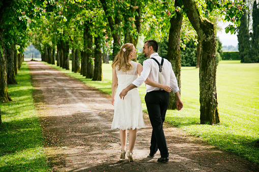 Young couple in wedding dress walking in nature forest path. Having fun. Very happy.