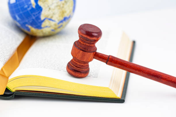 Book with gold edges, wood gavel, and globe placed on white background hold global justice and worldwide equity concepts