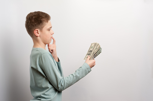 A boy with pensive expression holding a lot of money