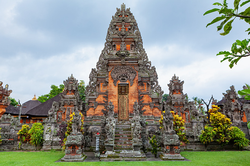 Details of traditional balinese hindu temple. Entrance gate with door, stone carving, Bhoma sprit face, guards sculptures. Popular travel destinations, art, culture festivals of Bali island, Indonesia