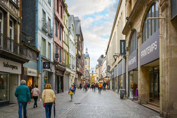Tourists enjoy a stroll along the shops on the Rue du Gros Orloge in Rouen France with the astronomical clock in the background. Tourists enjoy a stroll along the shops on the Rue du Gros Orloge in Rouen France with the astronomical clock in the background. Rouen, capital of the northern French region of Normandy, is a port city on the river Seine. Important in the Roman era and Middle Ages, it has Gothic churches, such as Saint-Maclou and Saint-Ouen, and a cobblestoned pedestrian center with medieval half-timbered houses. rue du gros horloge photos stock pictures, royalty-free photos & images