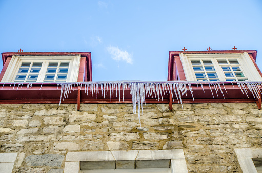 Ice stalactites from an old house gutter during winter day