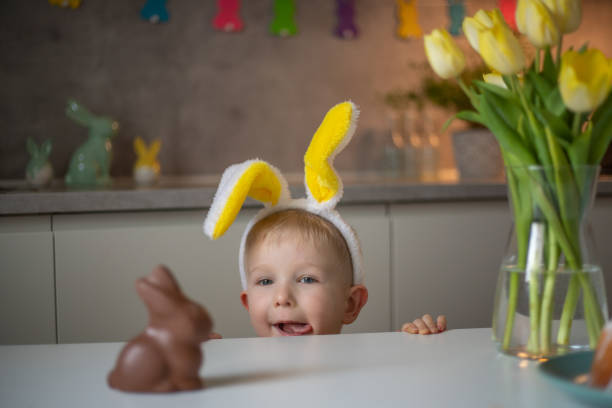 istock A cute little boy wearing bunny ears on Easter day wants to eat a chocolate easter bunny. A child plays egg hunt for Easter. Charming child celebrates Easter at home 1465388436