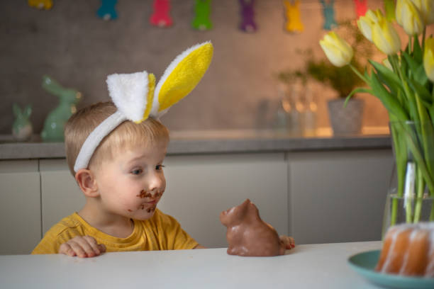 istock A cute little boy wearing bunny ears on Easter day is eating a chocolate Easter bunny. A child plays egg hunt for Easter. Charming child celebrates Easter at home 1465388601