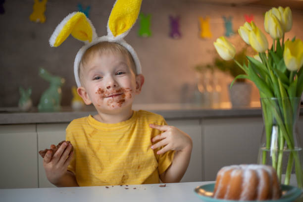 istock A cute little boy wearing bunny ears on Easter day is eating a chocolate Easter bunny. A child plays egg hunt for Easter. Charming child celebrates Easter at home 1465388602