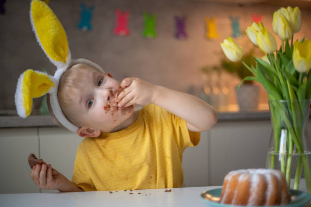 istock A cute little boy wearing bunny ears on Easter day is eating a chocolate Easter bunny. A child plays egg hunt for Easter. Charming child celebrates Easter at home 1465388674