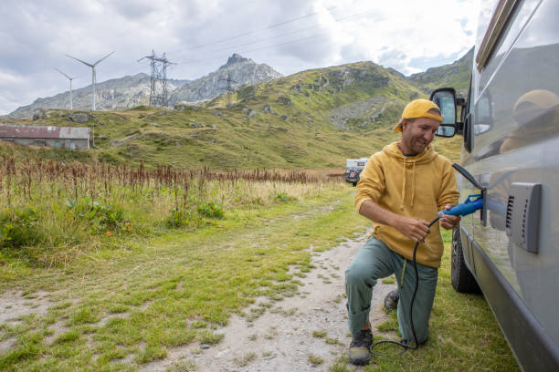 istock Man plugging electric vehicle, camper van in mountain settings 1465414145