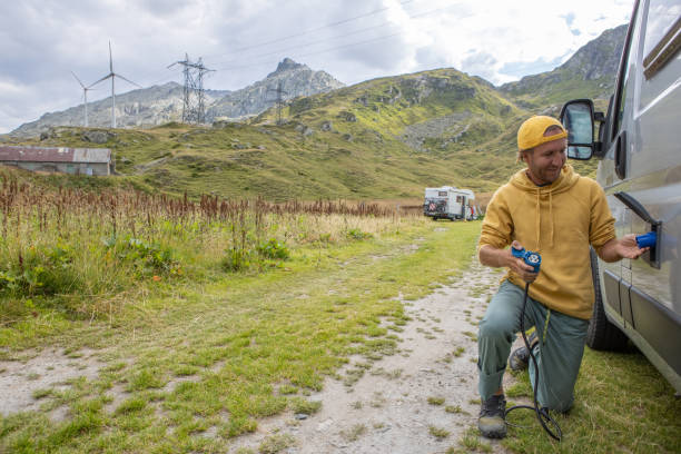 istock Man plugging electric vehicle, camper van in mountain settings 1465414159
