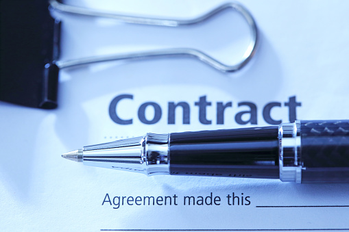 A close up of a  ballpoint pen resting on top of a contract that is ready for signing.