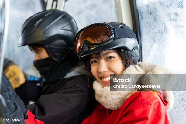 アジアの夫婦が冬休みにスノーボードとスキーの練習のためにケーブルカーで雪山の頂上に登る