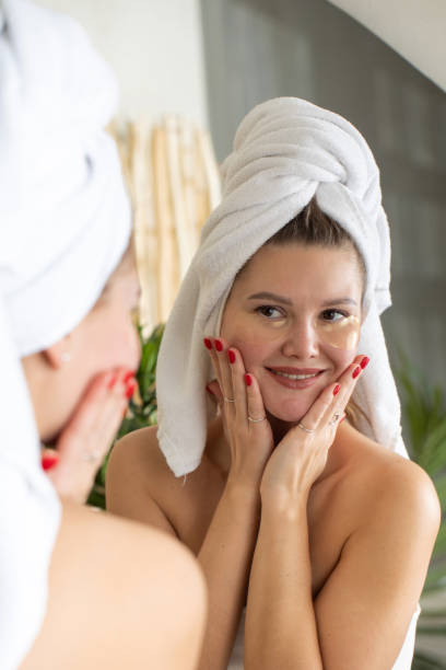 istock Attractive woman with patches under her eyes looks at her reflection in the mirror while smiling. 1465432990