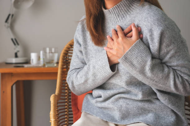 immagine ravvicinata di una donna con le mani sul petto, attacco cardiaco improvviso, che soffre di dolore toracico - arresto cardiaco foto e immagini stock