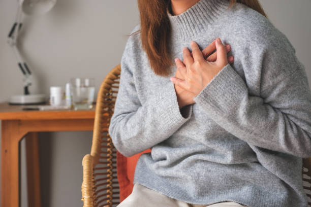 closeup image of a woman with hands on chest, sudden heart attack, suffering from chest pain - kalp krizi stok fotoğraflar ve resimler