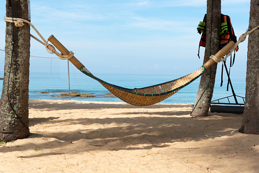 A wooden hammock on the beach and blue sky background.