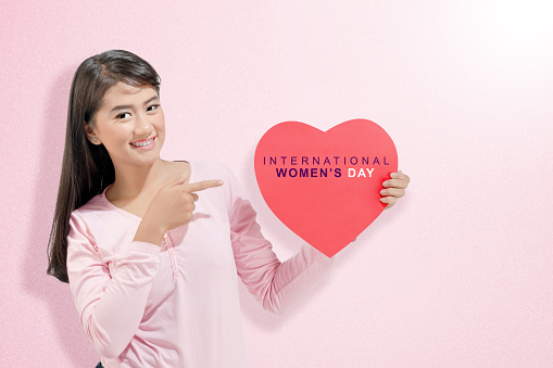 Asian woman showing heart with International Women's Day text. International Women Day