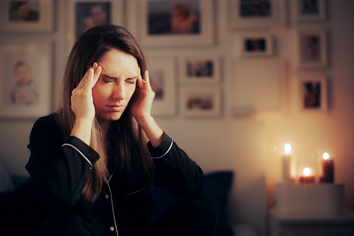 Mujer estresada que sufre una migraña por la noche antes de irse a dormir photo