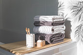 Bath spa soap towels pile soft textile cotton washcloth on wooden tabletop at sunny bathroom blurred background