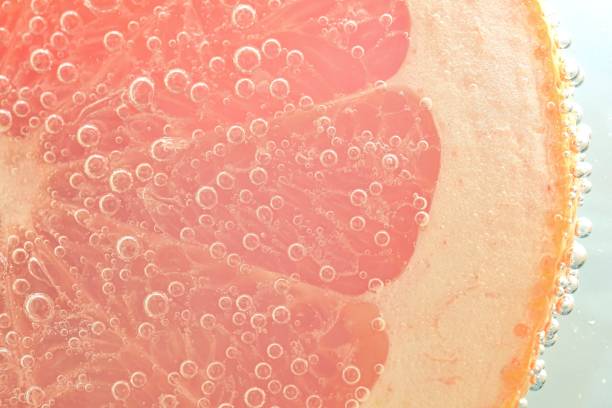 istock Close-up of fresh grapefruit slice on white background. Slice of red grapefruit in sparkling water on white background, close-up. Horizontal image 1465448087