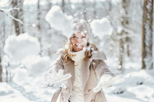 Teenage girl enjoying the the winter and the snow. The girl is jumping in the air and throwing the snow up.\nShot with Canon R5