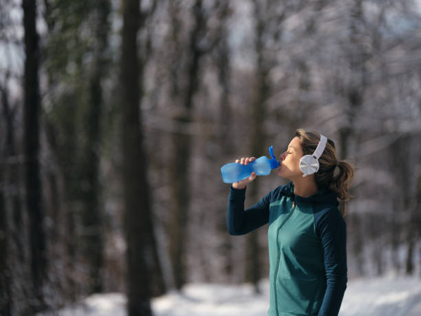 istock Athletic woman drinking water on a break in winter day at forest. 1465452678