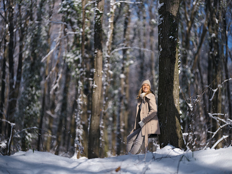 Happy woman enjoying while spending a winter day on snow in the forest. Photographed in medium format.