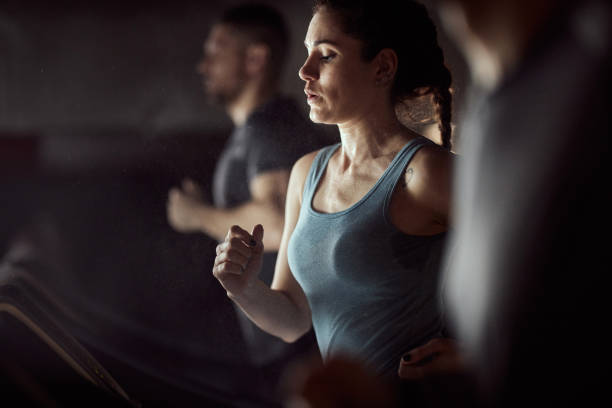 wysportowana kobieta rozgrzewająca się na bieżni na siłowni. - jogging running motivation group of people zdjęcia i obrazy z banku zdjęć