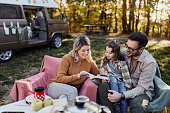 Happy family reading a book on picnic at trailer park.